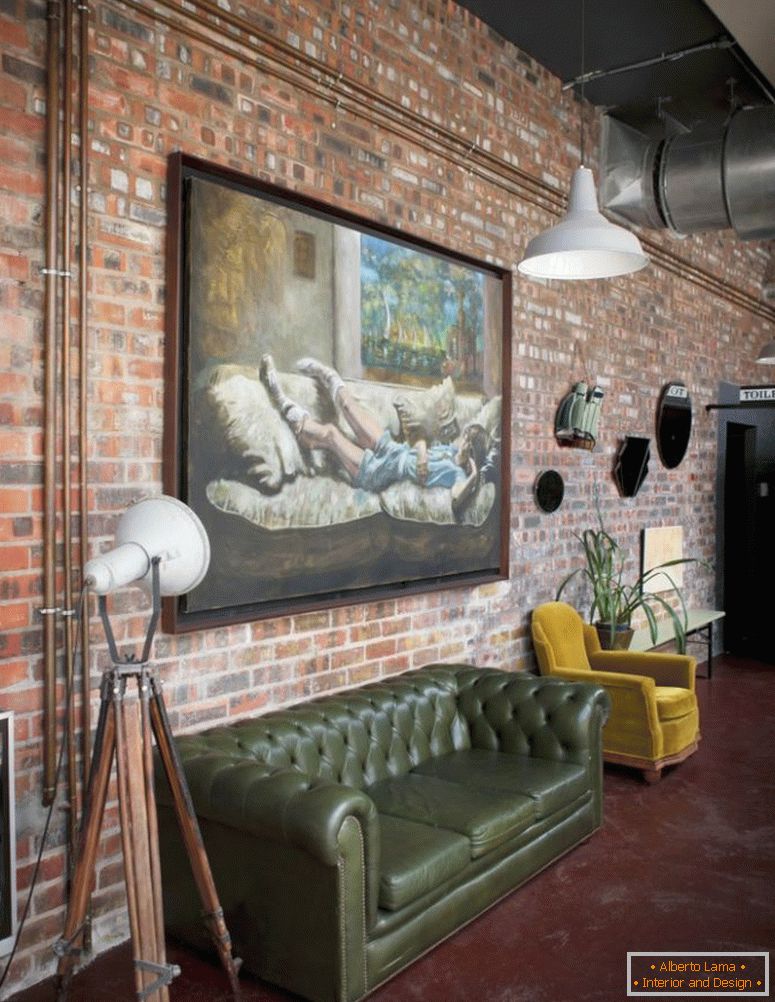 Veliko oljno sliko na opečnem zidu industrijskega slapa v apartmaju z retro kavčem in fotelj