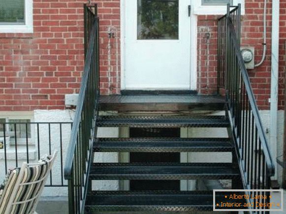 Majhen kovinski verand z stopniščem v opečno hišo
