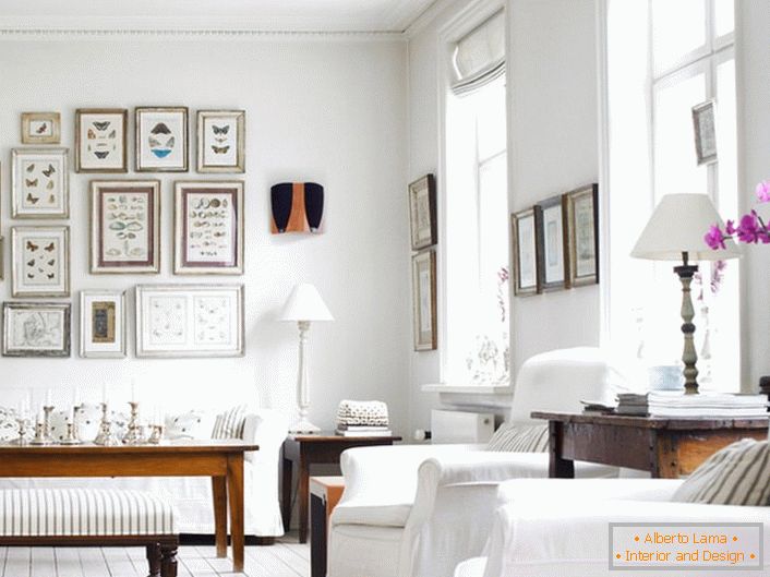 Udobna dnevna soba v skandinavskem slogu je izdelana v beli barvi. Zanimivo je, da okrasite steno z okvirji različnih velikosti.