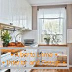 Belo pohištvo s pulti iz naravnega lesa v kuhinji