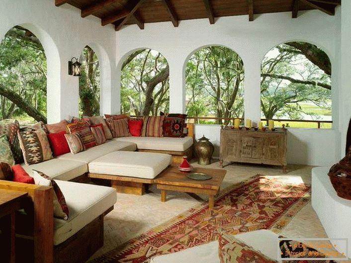 Veranda na deželi je urejena v skladu s sredozemskim slogom. Zanimivo je dekor z veliko barvnimi blazinicami.
