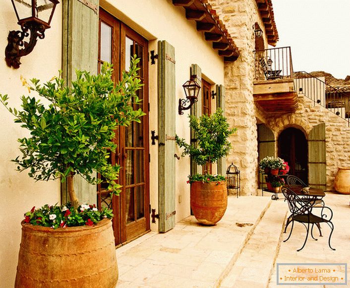 Patio в средиземноморском стиле украшают горшки с живыми растениями. Привлекательный дизайн, мебель с витиеватыми спинками, керамические горшки создают уютную, расслабляющую атмосферу. 