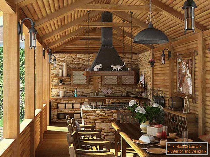 Majhna kuhinja z žarom na verandi hiše. V slogu države je razvidno, prvič, z dekoriranjem sten in stropa z lesenim okvirjem.