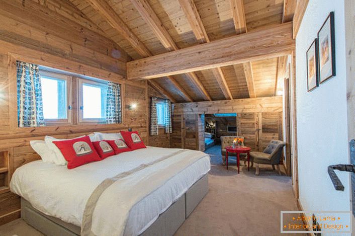 Prostorna spalnica v drugem nadstropju hiše iz lesene hiše. В соответствии со стилем кантри искусственный свет в комнате приглушен. 